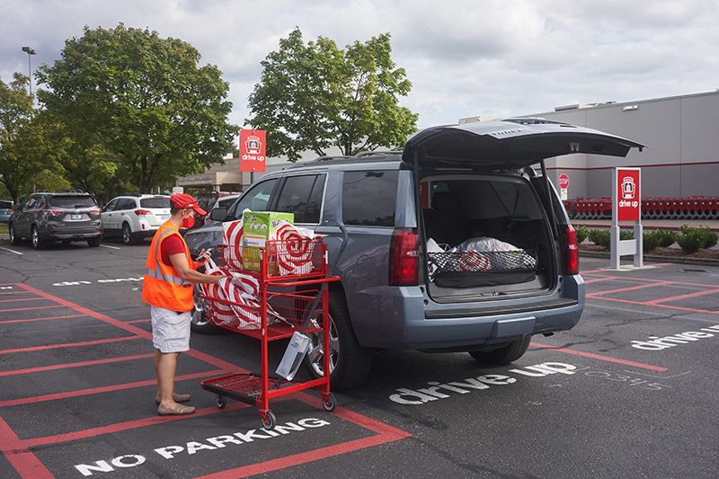 store employee brings bagged items out to a customers parked car during a pandemic